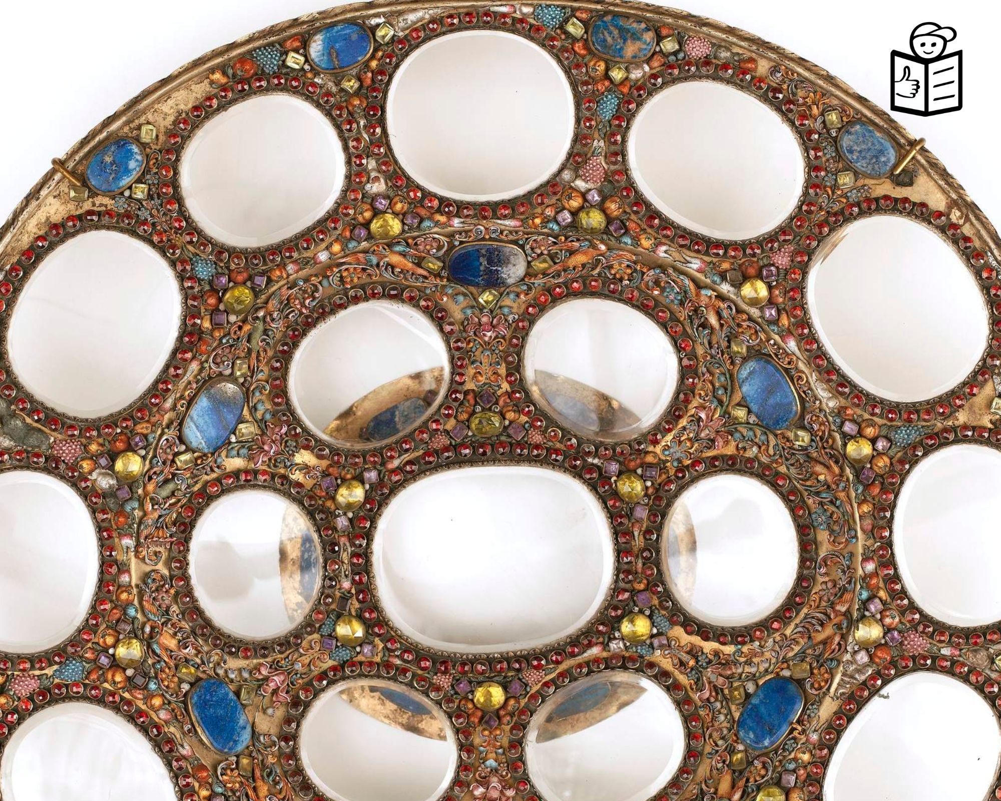 A close-up of a fragment of a ceramic object decorated with colourful stones. 